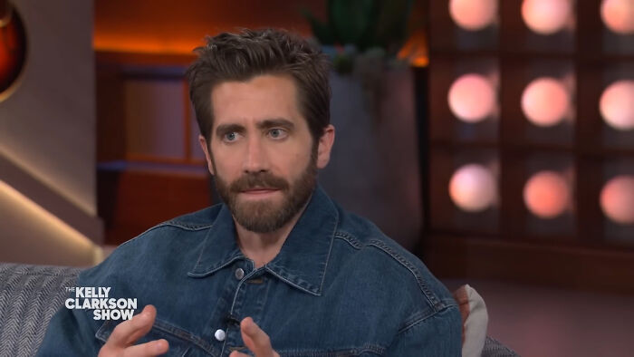 Actor in a denim jacket speaking on a TV talk show, illustrating moments when people met their idols in real life.