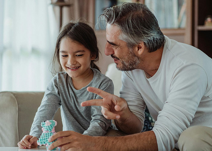 Middle-aged man bonding with young girl, showing affection and playfulness, reflecting non-biological parent relationship emotions.