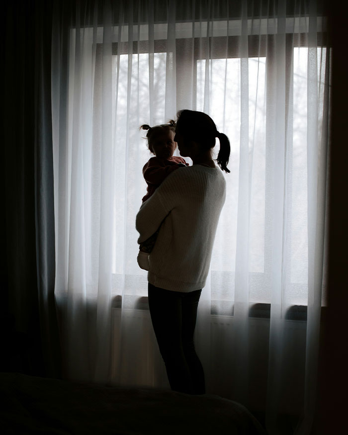 Silhouette of a parent holding a child near a window, representing gender identity and child support issues.