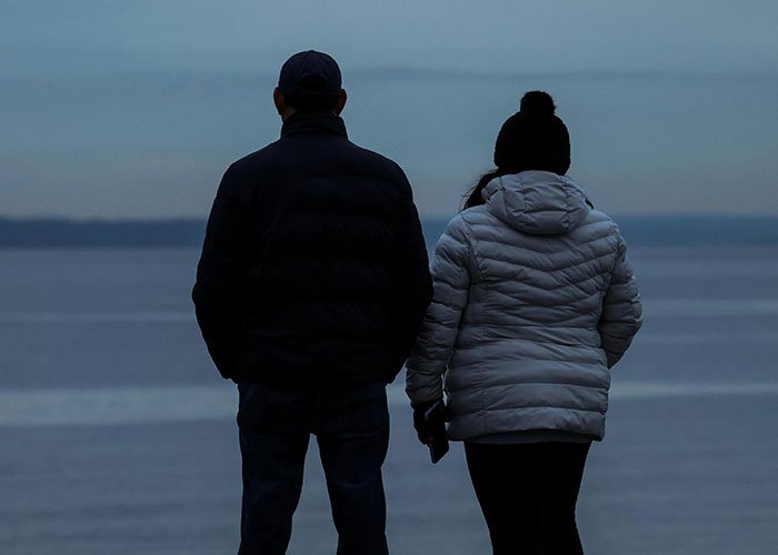 Two people wearing winter jackets stand by the water at dusk, capturing a moment with no filter family lore.