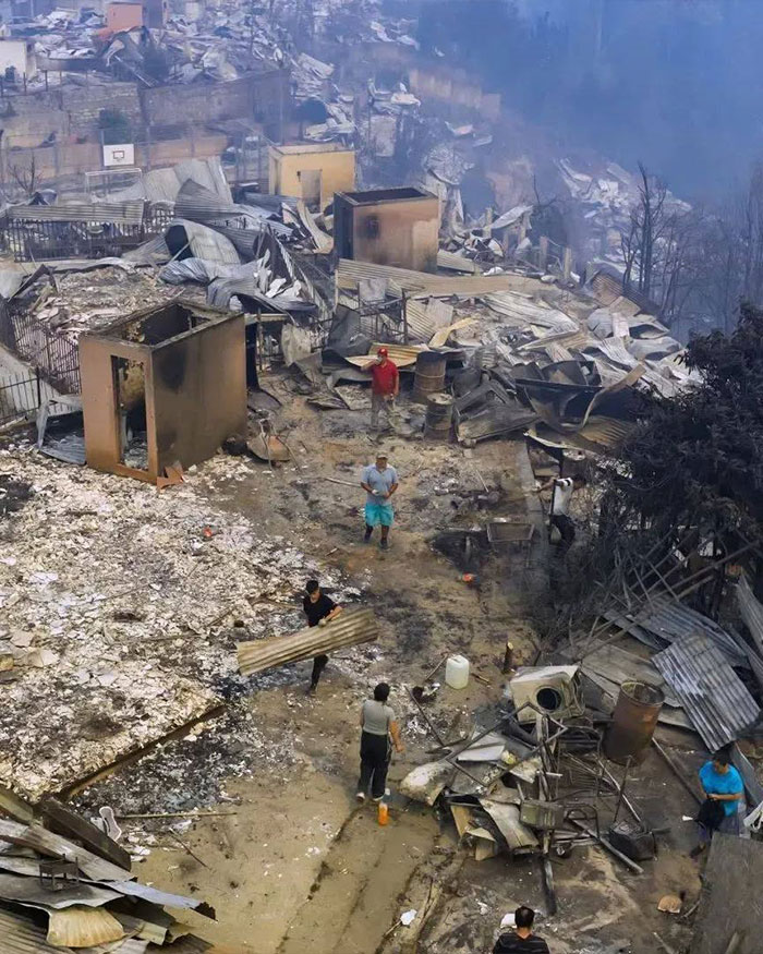 Volunteers amid charred ruins and debris clearing aftermath of Chile wildfires that burned down town overnight. Volunteers amid charred ruins and debris clearing aftermath of Chile wildfires that burned down town overnight.