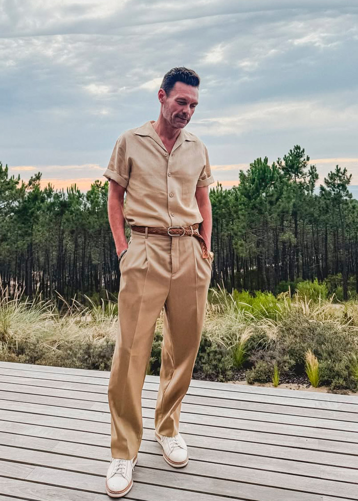 Ryan Seacrest standing outdoors in beige outfit, showing extremely skinny look of his face amid Hollywood trend concerns.