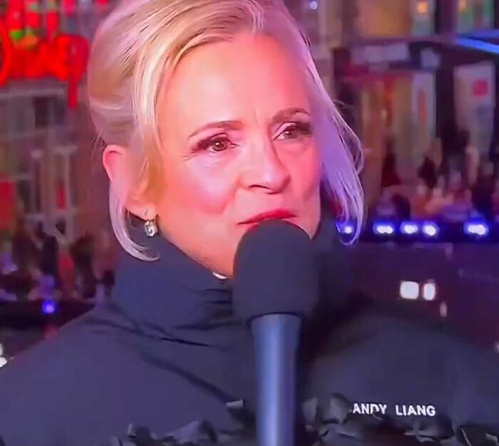 Amy Sedaris speaking into a microphone during a live broadcast, sparking transphobic controversy on CNN.