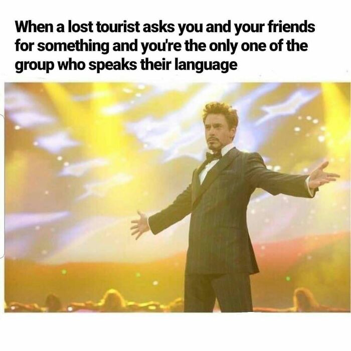 Man in suit confidently standing on stage with arms outstretched, illustrating hilarious travel memes about language skills.