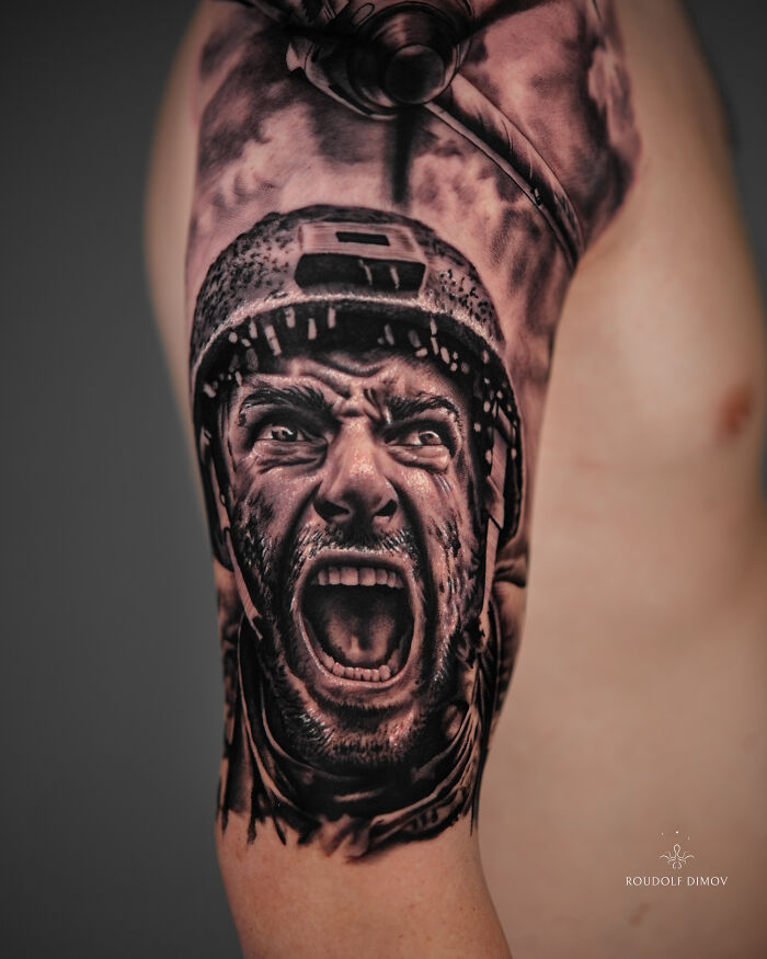 Realistic tattoo of a screaming soldier wearing a helmet, showcasing impressive detail in black and gray ink on upper arm.