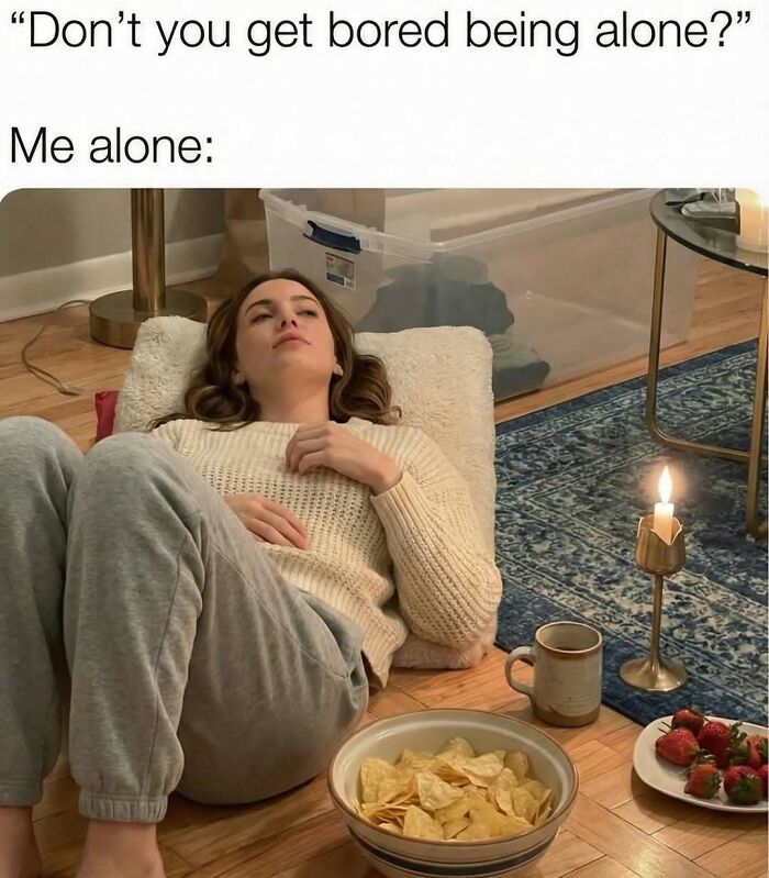 Person lying on floor with snacks and a candle, illustrating funny memes to distract from boredom and being alone.