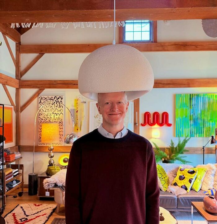 Tall man standing under a low hanging lamp in a colorful living room, illustrating common struggles for tall people.