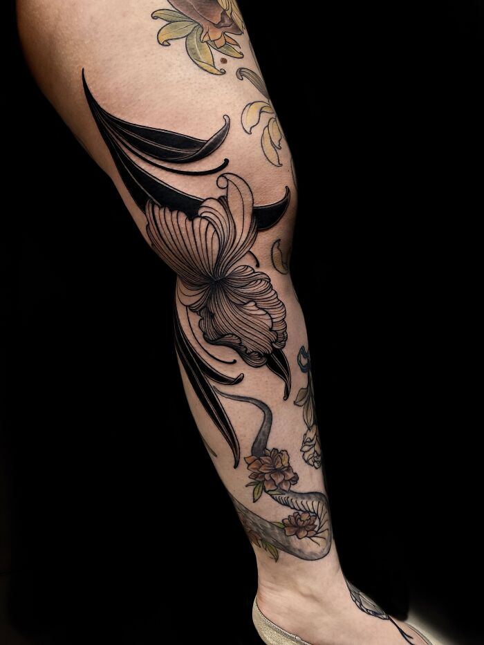 Floral and abstract black tattoos on a leg showcasing cool tattoo designs that look almost unreal with fine details.