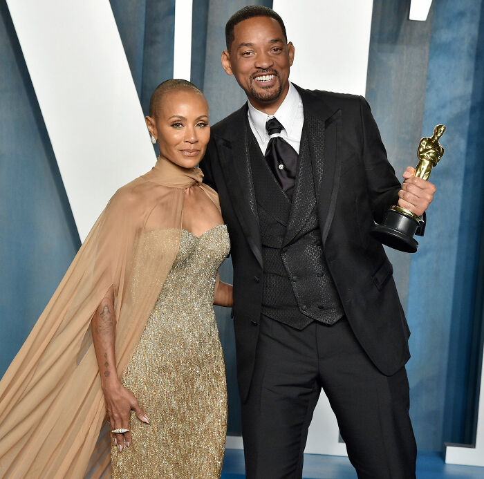 Will Smith smiling in a black suit holding an award, accused of harassing and deliberately grooming fellow musician.