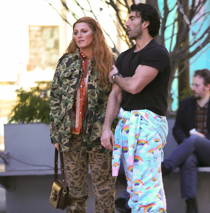 Blake Lively in camo outfit and man in rainbow pants having conversation outdoors, related to Taylor Swift leaked texts. Blake Lively in camo outfit and man in rainbow pants having conversation outdoors, related to Taylor Swift leaked texts.