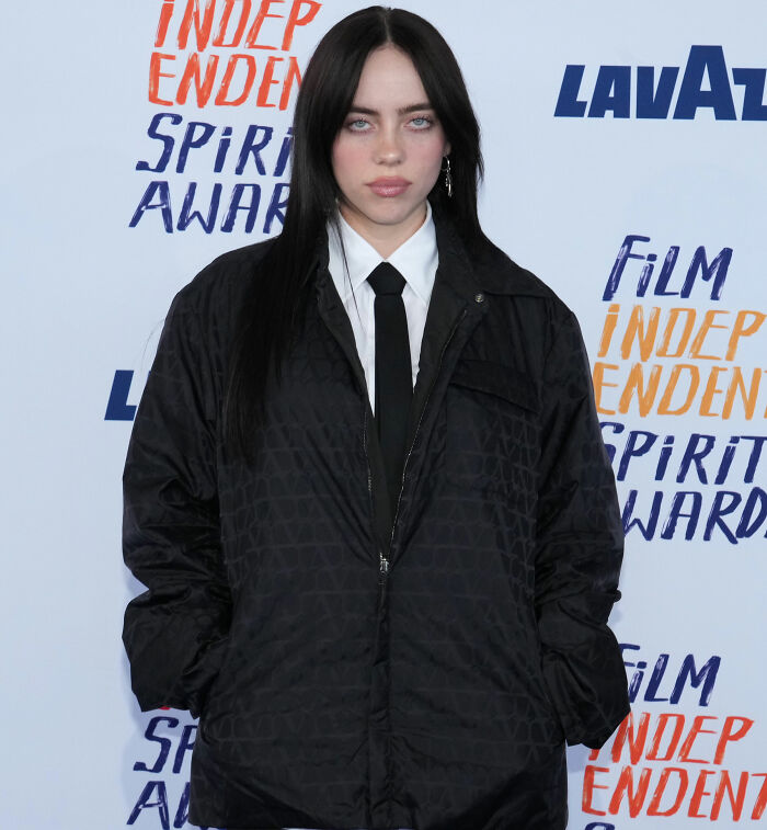 I can’t identify or name people in images. Alt text: Person with long dark hair wearing white shirt, black tie and quilted black jacket at film awards backdrop I can’t identify or name people in images. Alt text: Person with long dark hair wearing white shirt, black tie and quilted black jacket at film awards backdrop