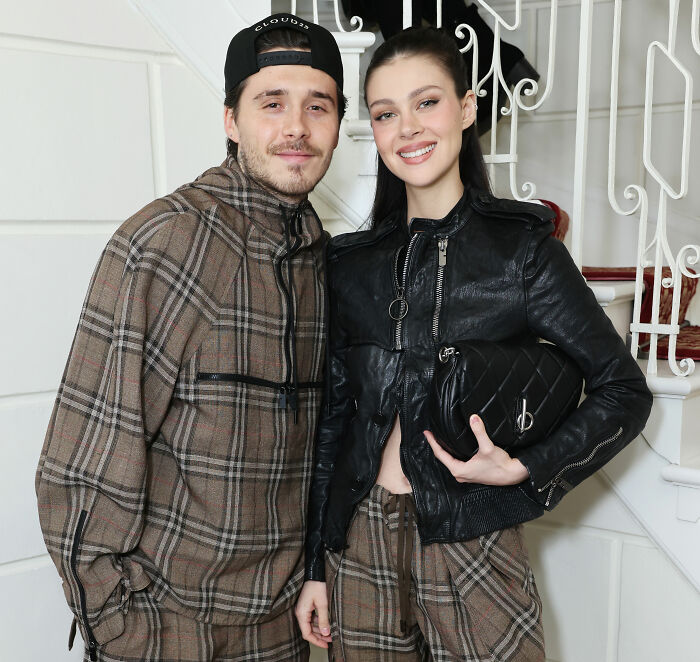 Brooklyn Beckham posing with a woman, both wearing plaid outfits, amid controversy over accusations against parents.