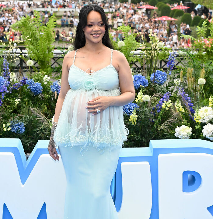 Rihanna in pale blue sheer lingerie-style gown cradling baby bump at outdoor floral event - distorted lingerie photos