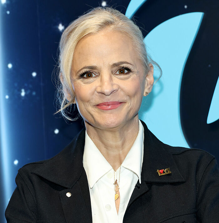 Amy Sedaris smiling at an event, wearing a black jacket and white shirt, related to transphobic jab controversy on CNN.