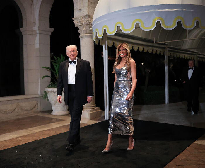 Melania Trump in a silver dress and Donald Trump in a tuxedo at Mar-a-Lago, highlighting body language and interaction. Melania Trump in a silver dress and Donald Trump in a tuxedo at Mar-a-Lago, highlighting body language and interaction.