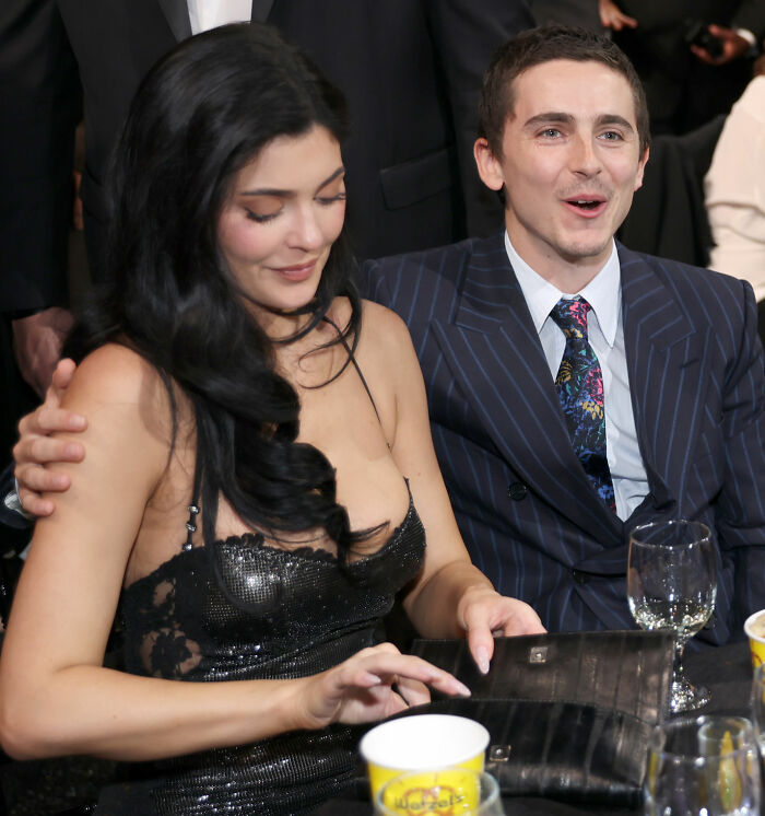 Timothée Chalamet seated beside Kylie Jenner at an event, dressed formally, engaging with the crowd around them Timothée Chalamet seated beside Kylie Jenner at an event, dressed formally, engaging with the crowd around them