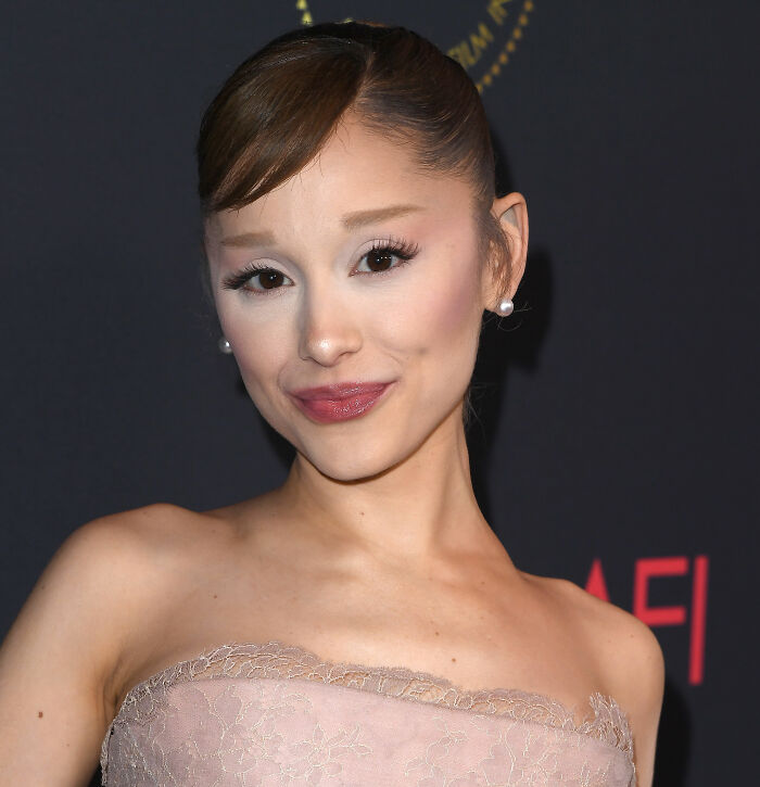 Ariana Grande posing at an event, showcasing unusual and bizarre mannerisms sparking numerous fan theories. Ariana Grande posing at an event, showcasing unusual and bizarre mannerisms sparking numerous fan theories.