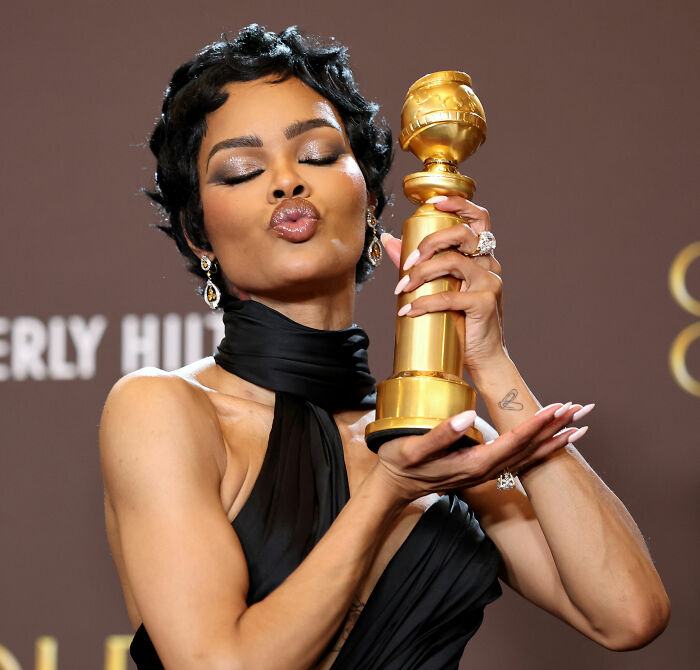 Woman holding a Golden Globe award, celebrating wins as the Academy releases 2026 Oscar nominations event unfolds.