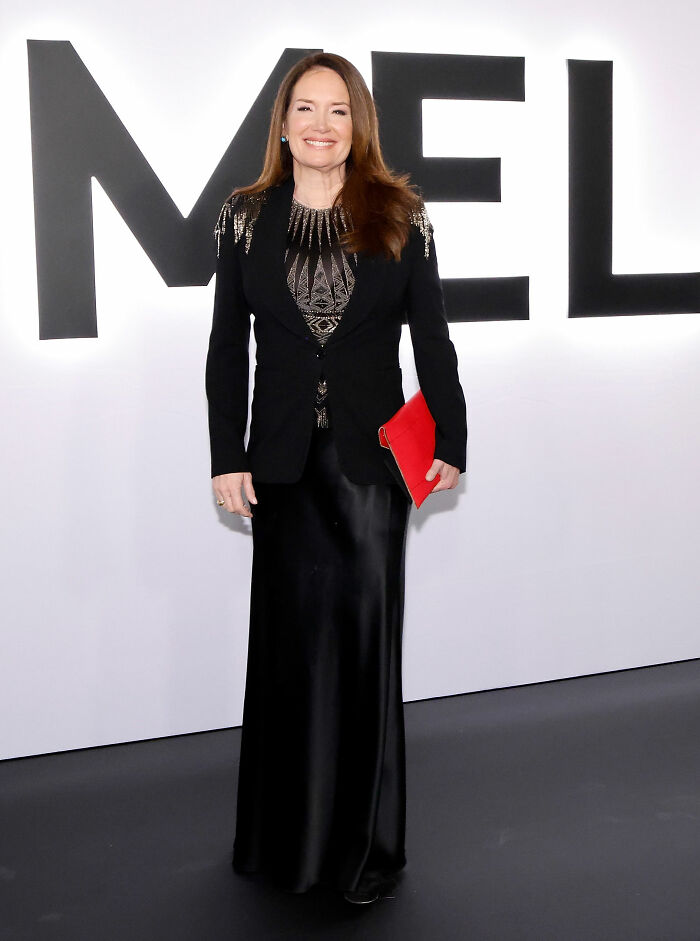 Woman in black outfit holding red clutch at event showcasing worst MAGA looks from Melania Trump documentary premiere.