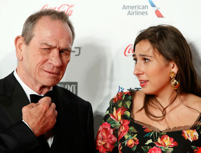 Tommy Lee Jones in a tuxedo with daughter Victoria in a floral dress at an event amid firing joke resurfacing discussion.