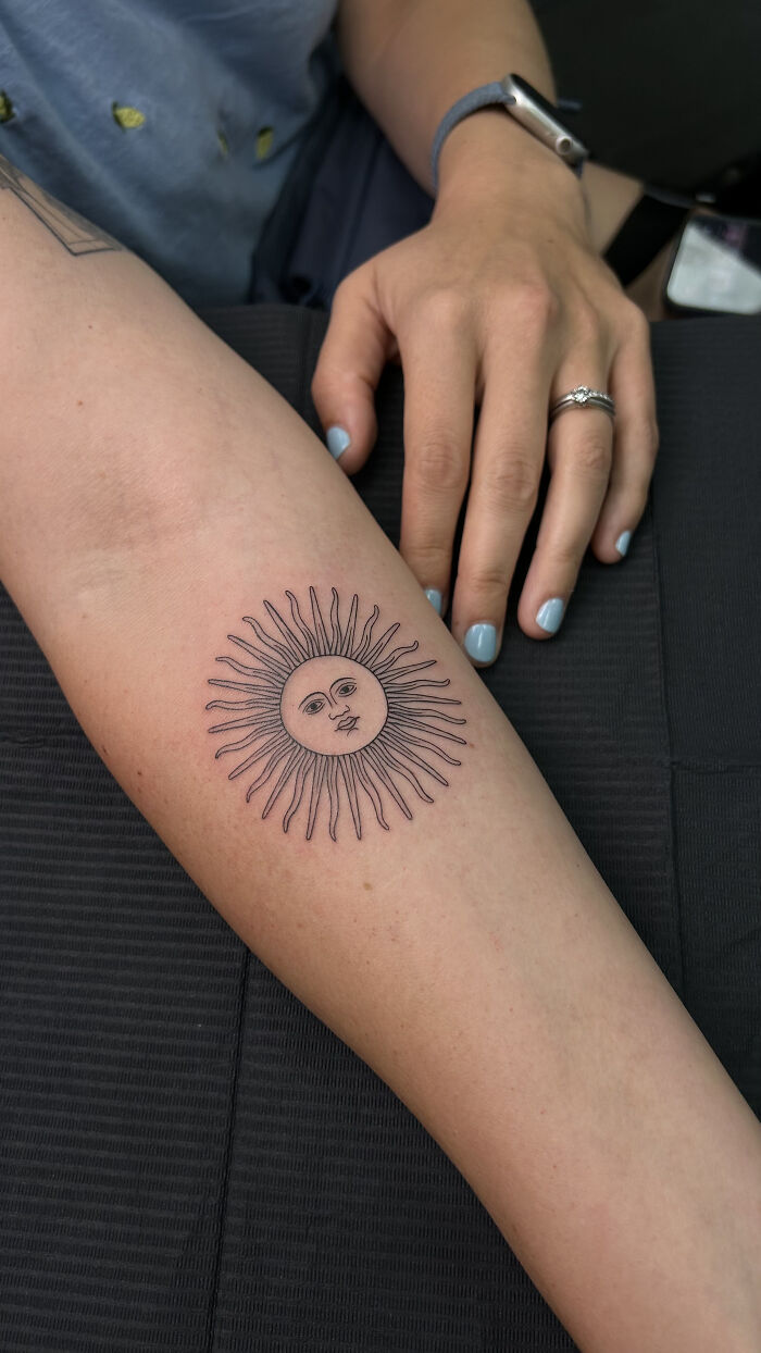 Minimalist sun tattoo on forearm with delicate linework, showcasing tattoos that look so cool they almost don’t feel real.