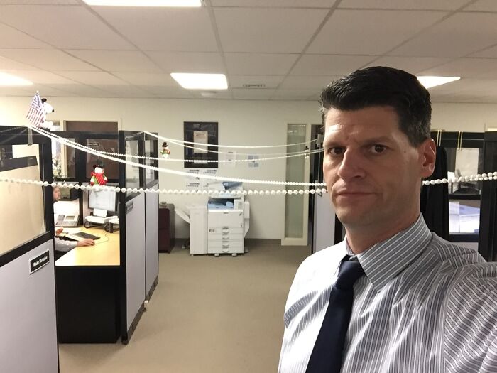 Tall man in office cubicle setting, highlighting everyday struggles only tall people face while working indoors.