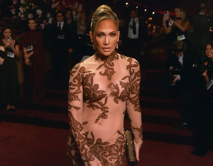 Jennifer Lopez in a sheer embroidered gown at a red carpet event, related to GlamBOT King viral interaction at Golden Globes.