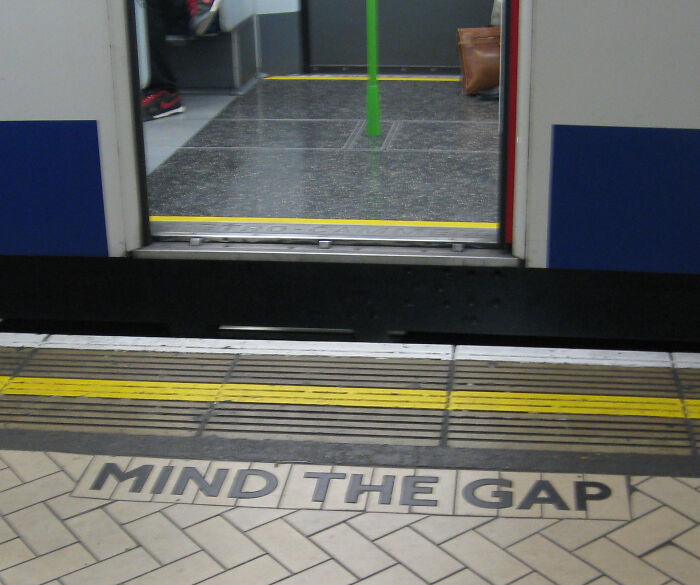 Mind the gap warning at a train station platform edge highlighting a common problem with shipping containers and transport safety.