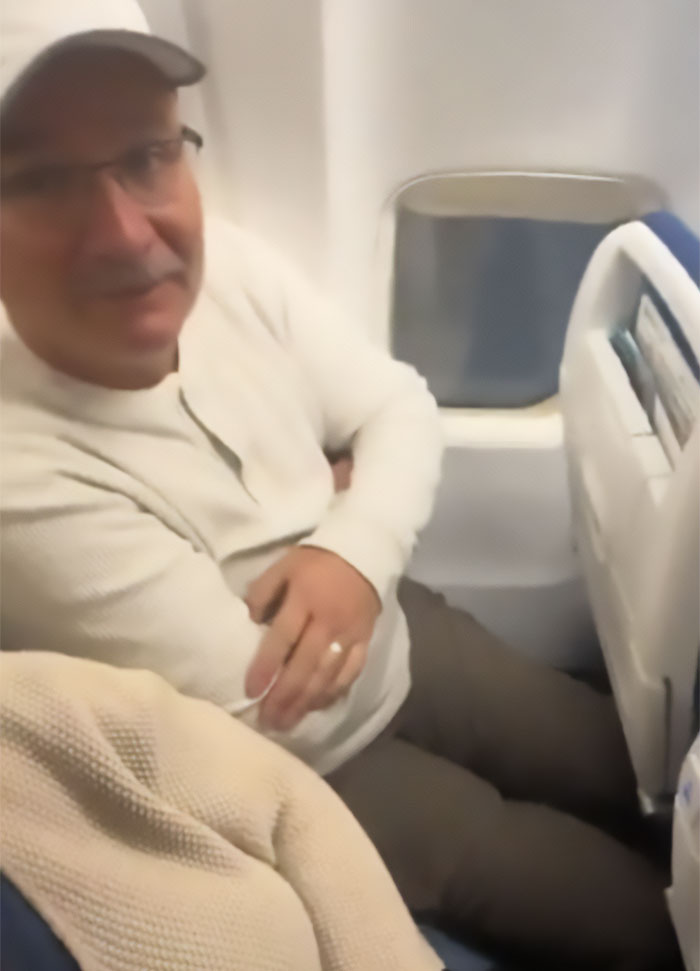 Man in cramped airplane seat showing sardine can seating with limited legroom by window Man in cramped airplane seat showing sardine can seating with limited legroom by window