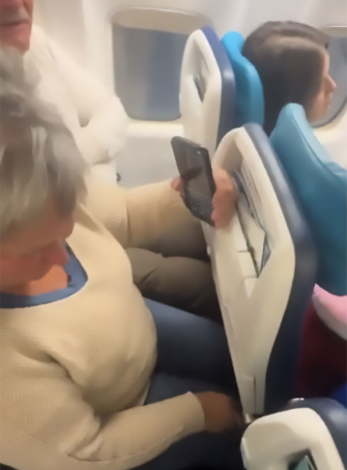 Cramped passengers in sardine can seating on a new plane, woman squeezed with minimal legroom and man holding phone. Cramped passengers in sardine can seating on a new plane, woman squeezed with minimal legroom and man holding phone.