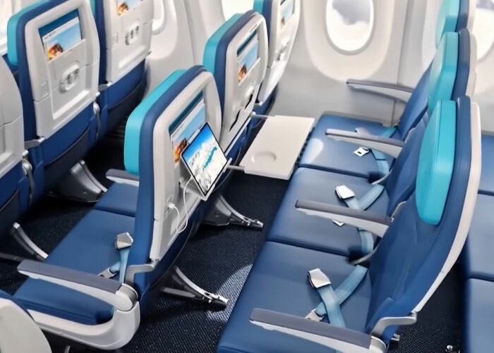 sardine can seating on new plane, cramped blue seats with narrow legroom, tray tables down and small seatback screens visible sardine can seating on new plane, cramped blue seats with narrow legroom, tray tables down and small seatback screens visible