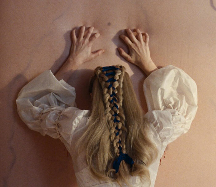 Woman with braided hair tied with blue ribbon wearing a white blouse, evoking Margot Robbie on-set relationship with Wuthering Heights co-star. Woman with braided hair tied with blue ribbon wearing a white blouse, evoking Margot Robbie on-set relationship with Wuthering Heights co-star.