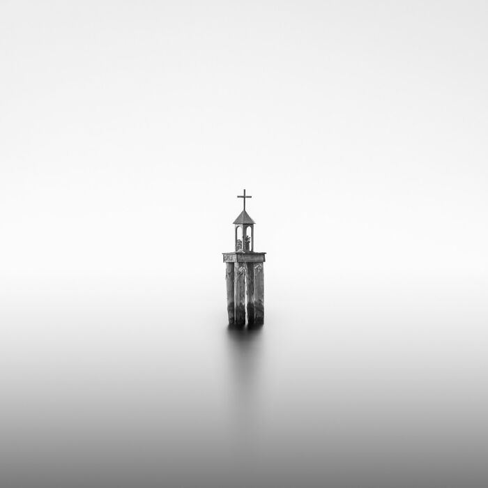 Minimalist black and white photo of a solitary structure in calm water, showcasing stunning animal photography elements.