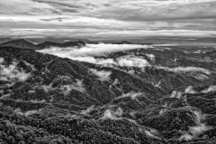Aerial view of mist-covered mountain ranges under a cloudy sky showcasing breathtaking exposure photography.