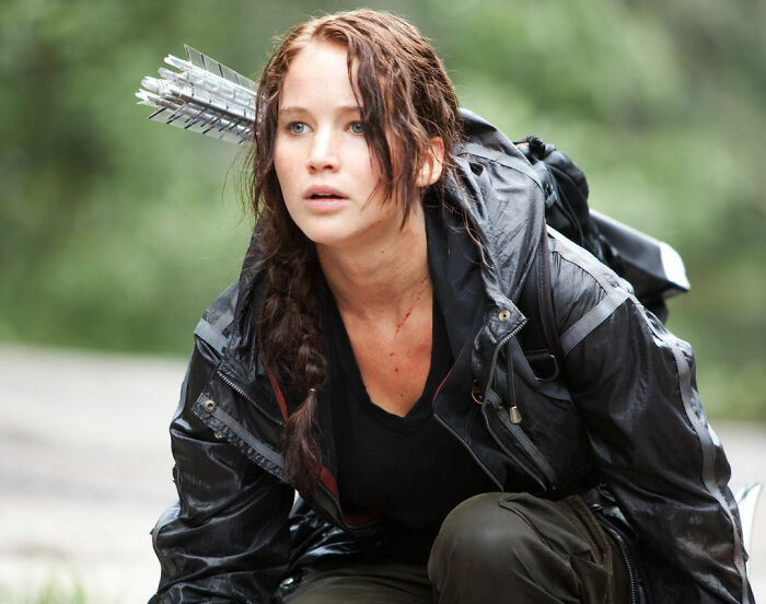 Actress in outdoor gear with arrows on back, portraying a character in a movie about celebrities and their downfall.