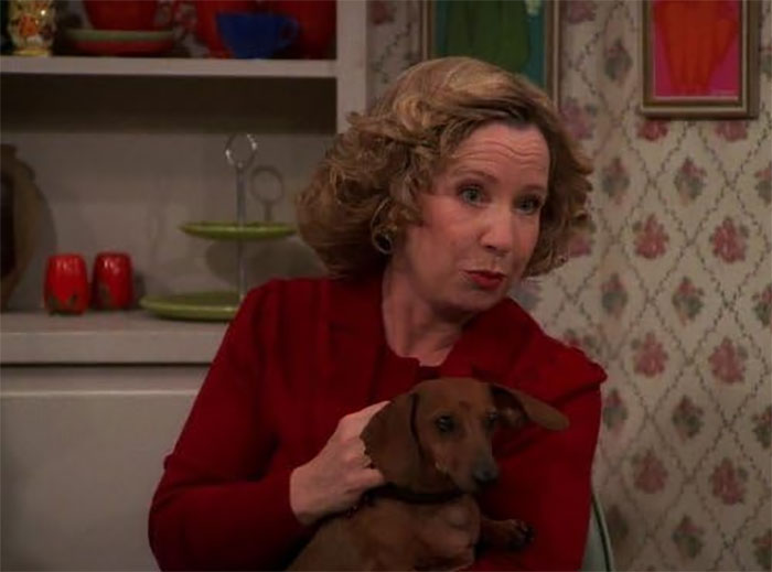 Woman in a red sweater holding a small brown dog, illustrating diva stars described by movie set workers.