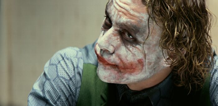 The Joker with white face paint and red lips, representing famous villains and the theme of pure evil.