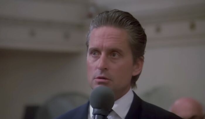 Actor in a suit speaking into a microphone, representing famous villains including Lord Voldemort pure evil debate.