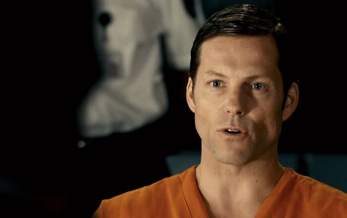 Man in orange prison jumpsuit speaking in a dark room, linked to discussion on Lord Voldemort pure evil and villains.