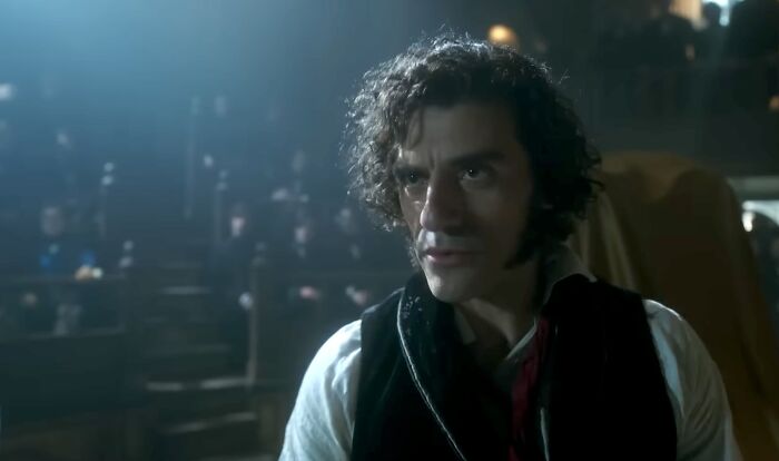Man with curly hair and intense expression in dimly lit room, illustrating famous villains including Lord Voldemort pure evil.