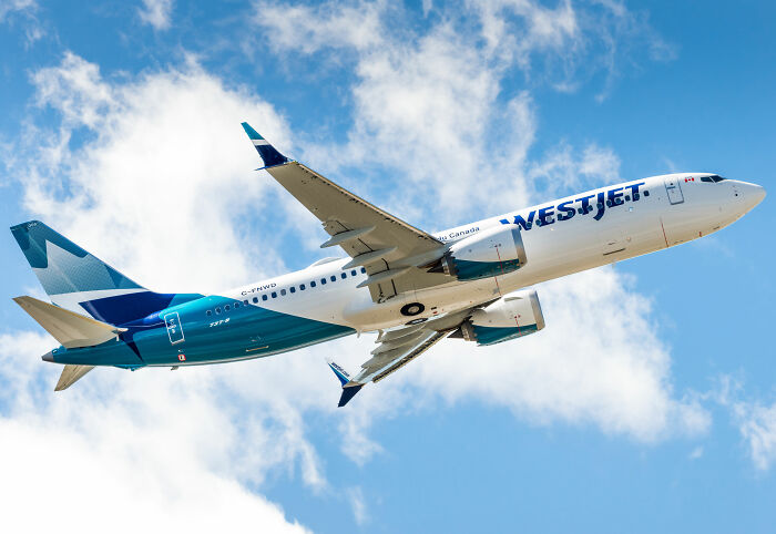 WestJet airplane in flight against blue sky, highlighting sardine can seating on new planes WestJet airplane in flight against blue sky, highlighting sardine can seating on new planes