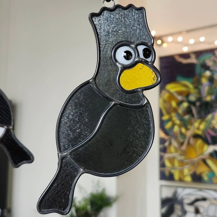 Stained glass sign of a cartoonish bird with a yellow beak, showcasing vivid pop culture icon art style.