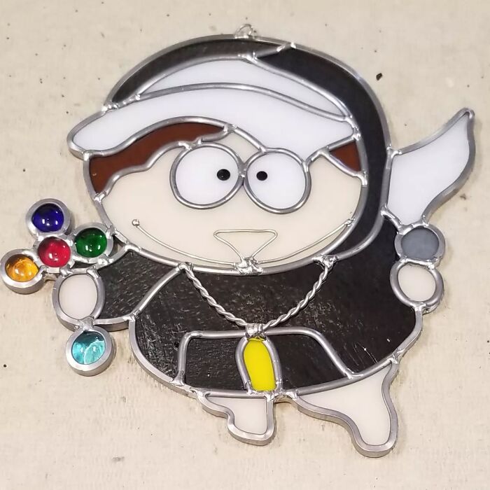 Stained glass pop culture icon resembling a cartoon character holding colorful gems and a white knife.