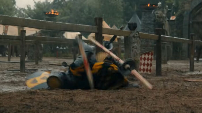 Knight falls during a medieval jousting tournament, with house sigils visible on shields and banners in the background Knight falls during a medieval jousting tournament, with house sigils visible on shields and banners in the background