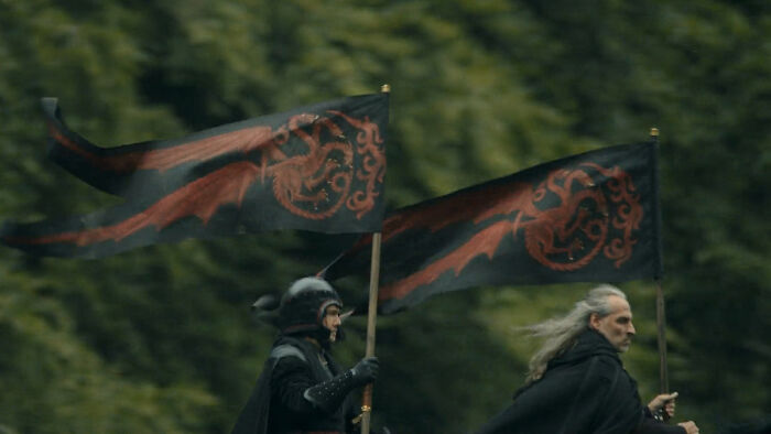 Two riders carry black flags with red dragon house sigils, representing every house sigil in A Knight of the Seven Kingdoms. Two riders carry black flags with red dragon house sigils, representing every house sigil in A Knight of the Seven Kingdoms.