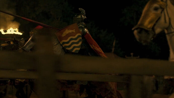 Medieval knight in armor holding a shield with house sigil during a night scene in Seven Kingdoms setting.