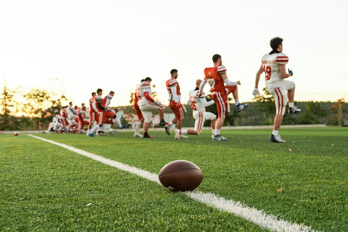 High school football players warming up on a field, highlighting moments of high school controversies and sports.