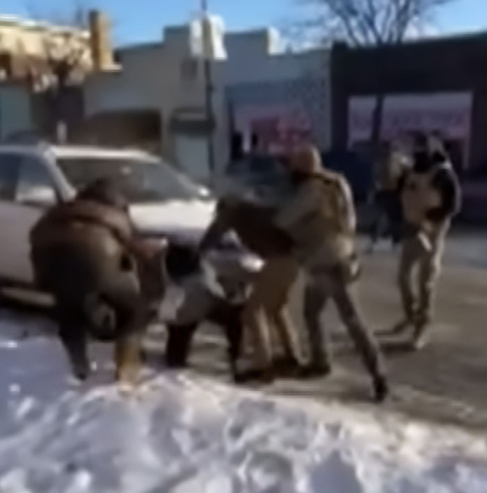Police officers detaining a person on a snowy street, illustrating a tense moment related to Alex Pretti's fate and government care.
