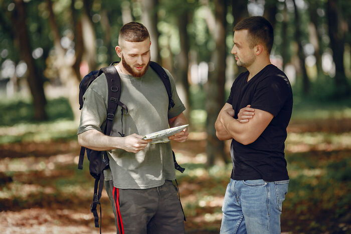 Two men outdoors, one with backpack showing a map, illustrating all you can eat buffet employees sharing gluttony stories.