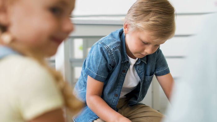 Young boy looking down thoughtfully in a casual setting, illustrating a scene from all you can eat buffet experiences.